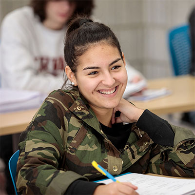 student taking notes and smiling