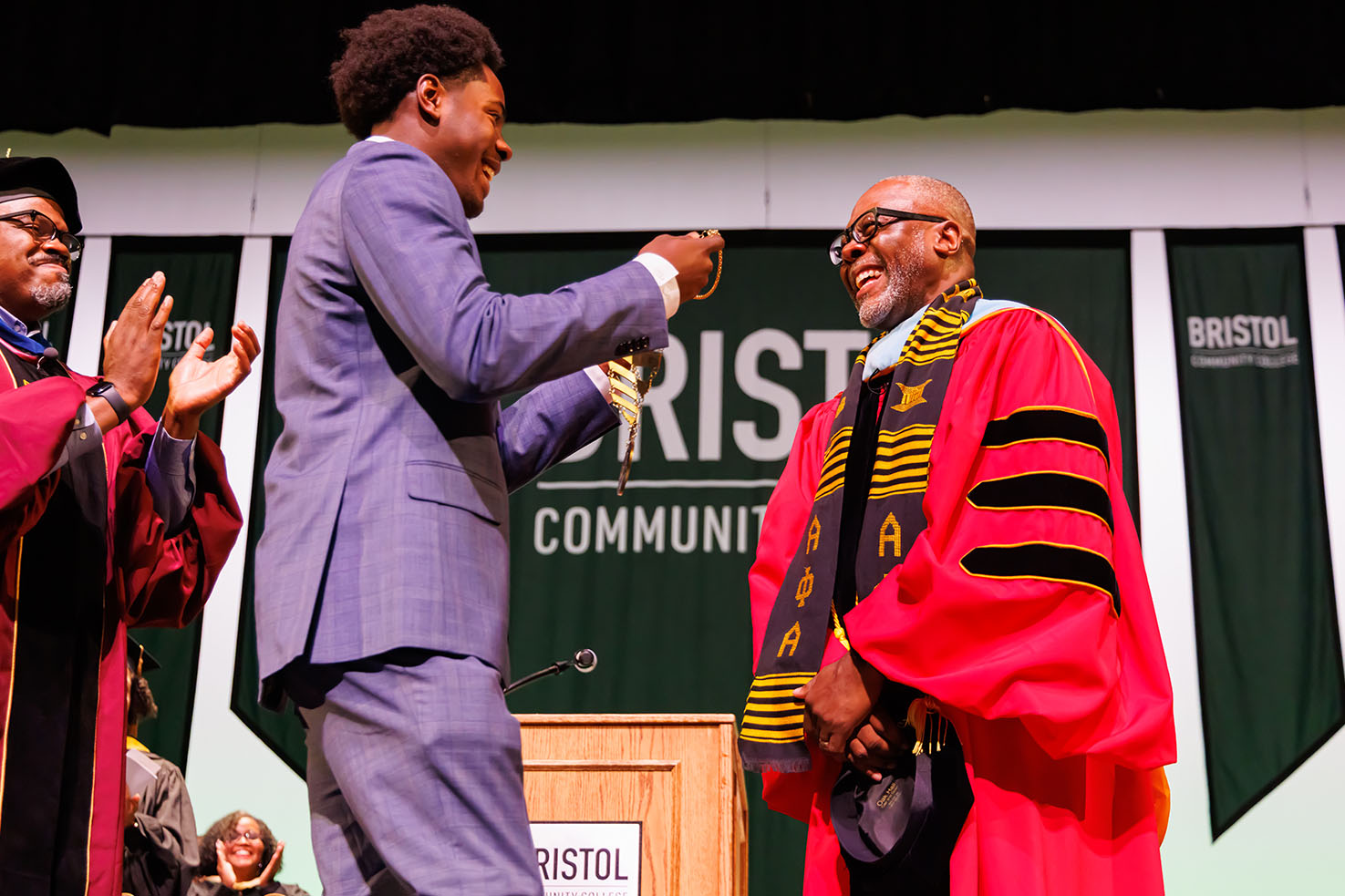Dr. Harris's son presenting Dr. Harris with the medallion on stage at Inauguration