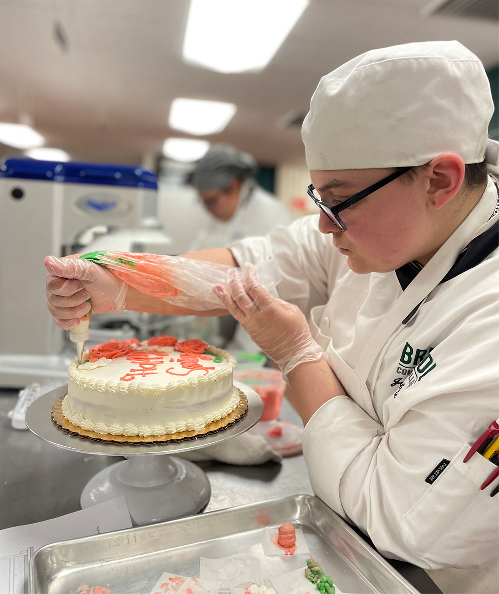 Baking and pastry arts student at Bristol decorating a cake