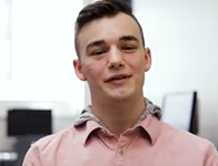 person with short brown hair and wearing a pink collared shirt