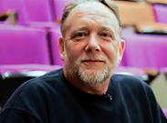 person with white hair and white goatee wearing a navy sweatshirt