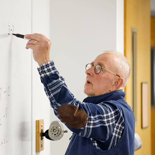 Professor writing math equation on whiteboard
