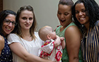 four people pose for the camera and one person is holding a baby