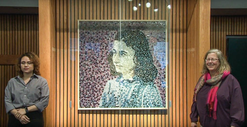 Art department chair Marisa Millard and a student standing by a portrait of Anne Frank made from buttons.