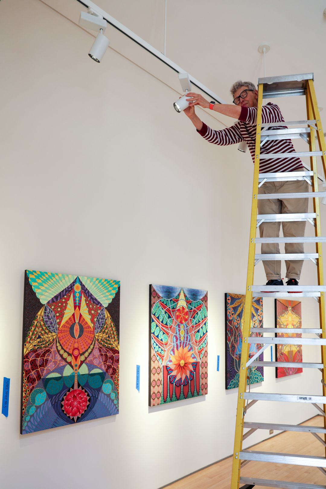 Art Gallery director Kathleen Hancock adjusting lighting for an exhibition
