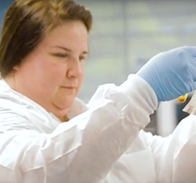 person wearing white lab coat and blue latex gloves