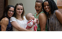 four people pose for the camera and one person is holding a baby