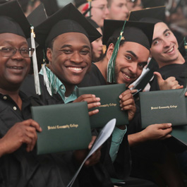 students smiling and holding their diploma covers