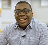 person with collared shirt and glasses smiling at the camera