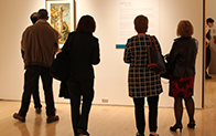 people standing near each other and looking at a wall hanging