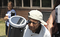 person wearing sideways baseball cap looks through telescope