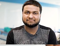 person with short brown hair and brown beard wearing a black and grey shirt