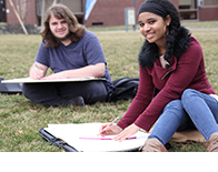 two art students sitting outside and drawing