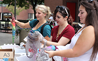 three students tie-dying tshirts with rainbow colors