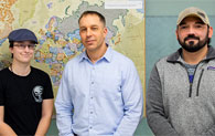 three people standing in front of map