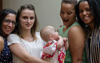 four individuals smiling for photo and one is holding a baby