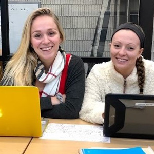 two people sitting behind table with laptops