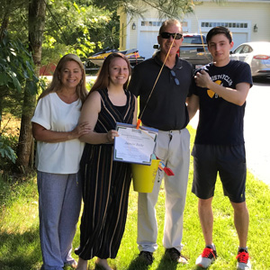 four people smiling at camera and one person holding certificate