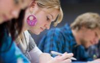 student with purple earrings writing in notebook