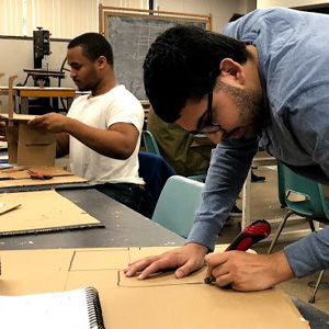 person tracing design on cardboard